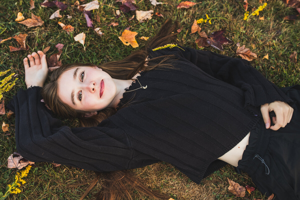 A cute smirk is on this senior girls face as she lays in a pile of leaves near park in Sewickley PA.