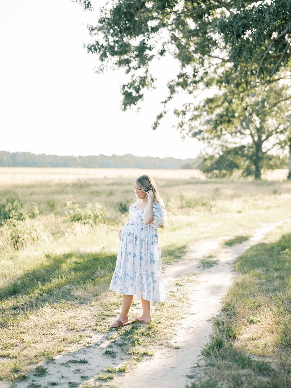 pregnant women holds belly in field