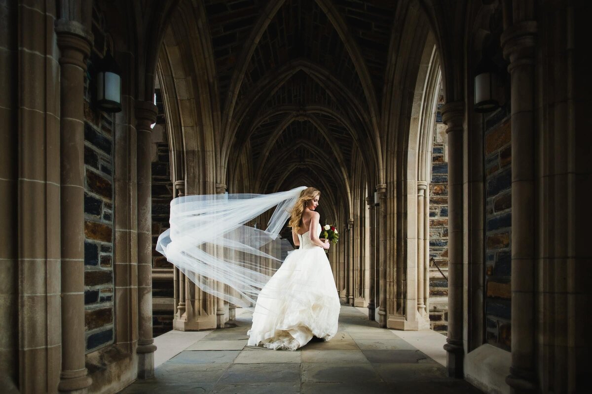 A bride walking through a corridor as her veil flows behind her.