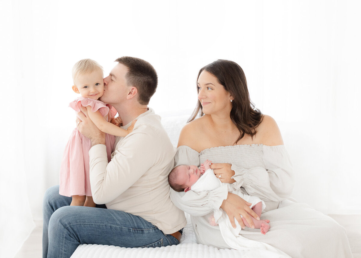 dad holding toddler hugging mom and newborn baby sister during boston newborn photoshoot