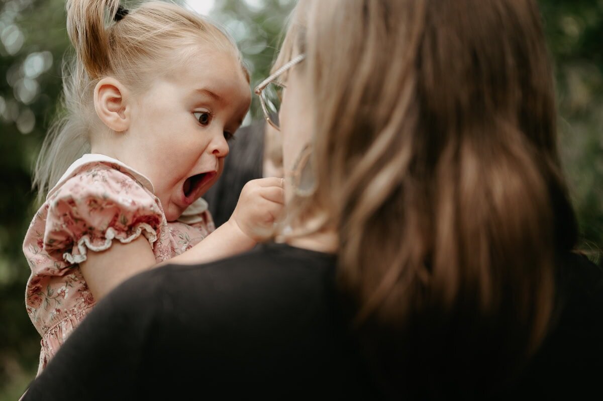 Mamma håller sin dotter i famnen och dottern gapar.