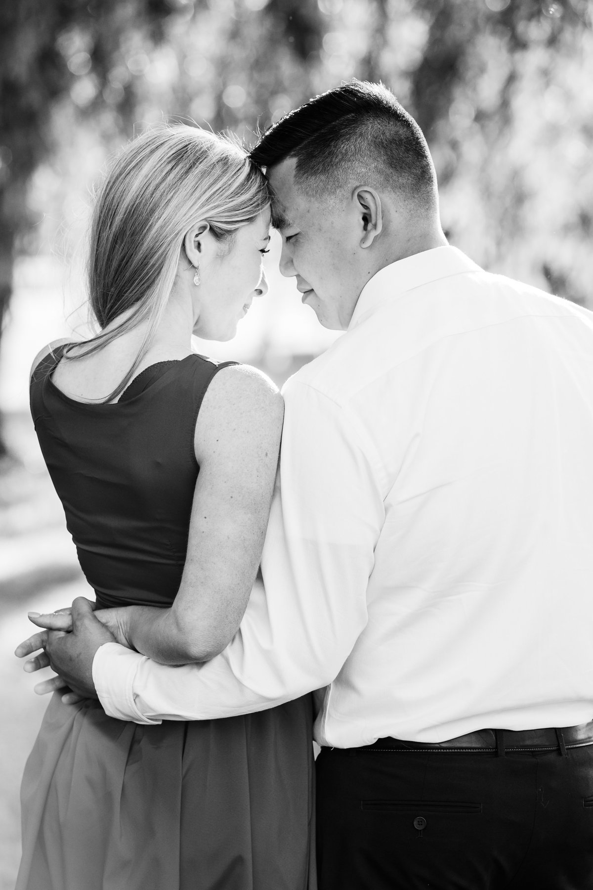 Eddy-wraps-his-arm-around-his-fiance-during-their-engagement-session-at-Jackson-park-in-Windsor-Ontario