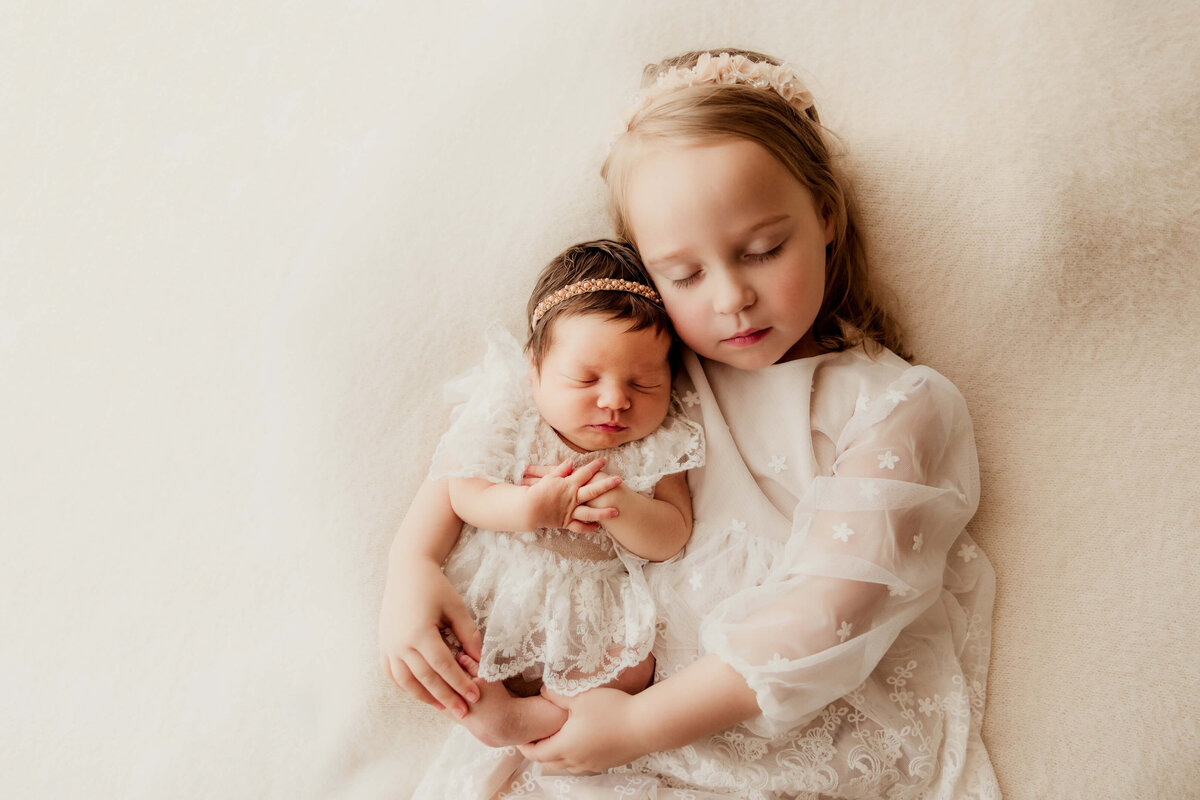 Older sibling holds her newborn baby sister.