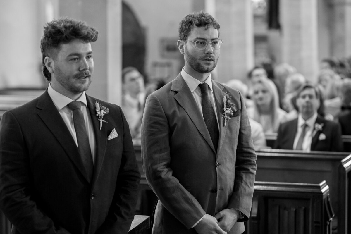 The groom waits for his bride at the end of the aisle