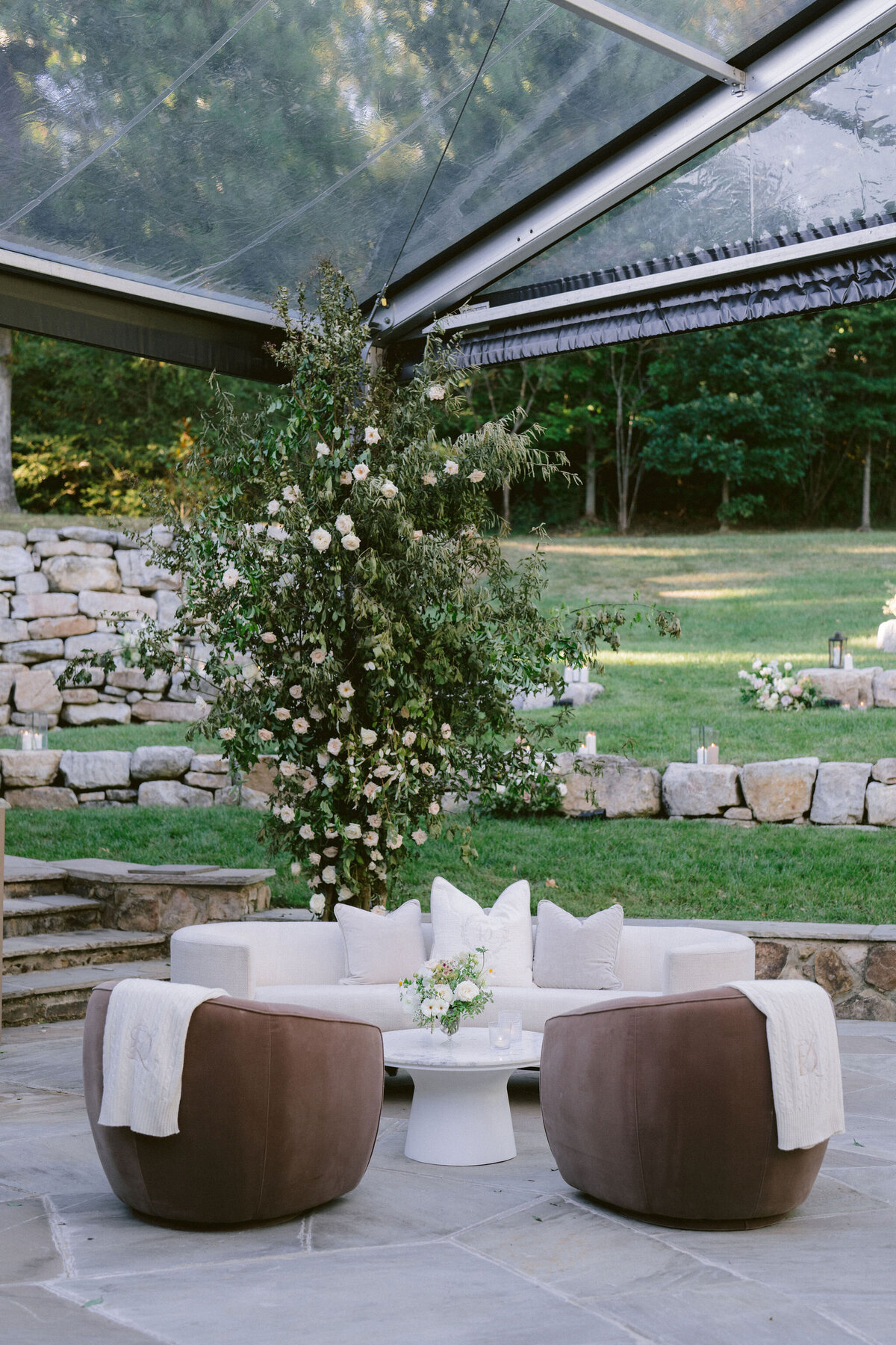 Lush garden inspired floral design growing in Bramble at Blackberry Farm for fall wedding reception. Growing floral installations on chandeliers and ceiling beams create garden setting for fall wedding reception. Timeless and elegant floral design in hues of white, cream, blush, and natural greens. Large trees with floral moments for outdoor wedding reception. Destination wedding at Blackberry Farm. Design by Rosemary & Finch Floral Design in Nashville, TN.
