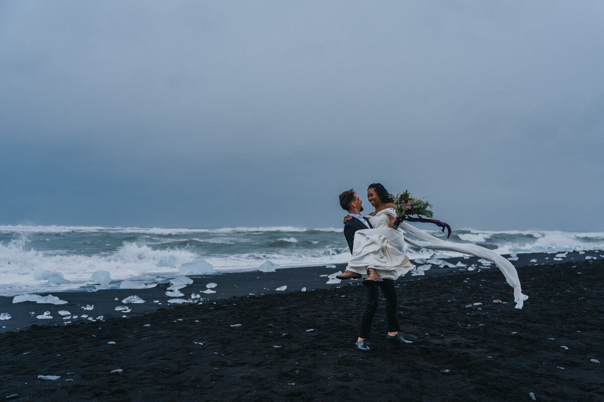 In the serene landscape of an Icelandic glacial lagoon, a couple shares a quiet moment together