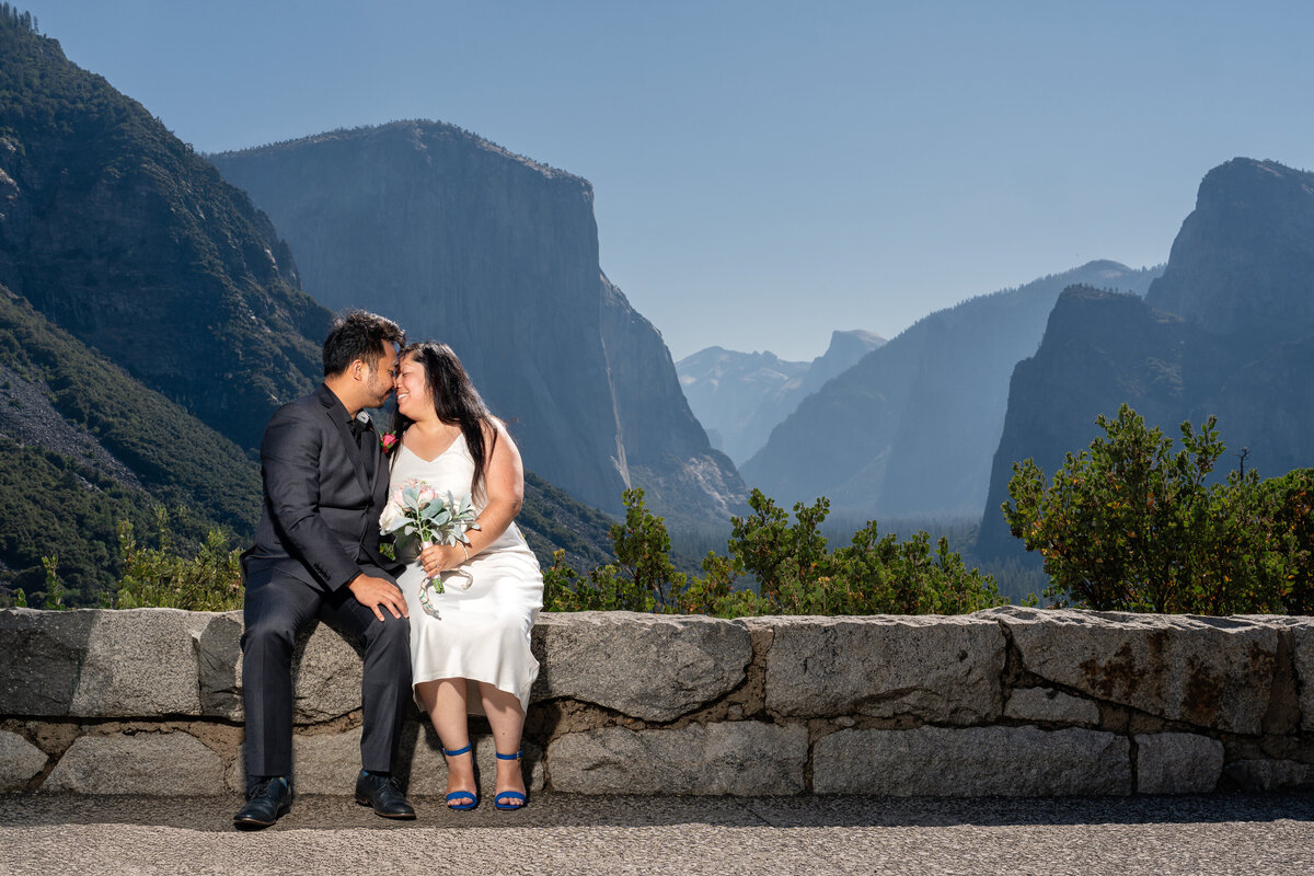 Bride and Groom eloping at Yosemite elopement at Tunnel View sitting and kissing.