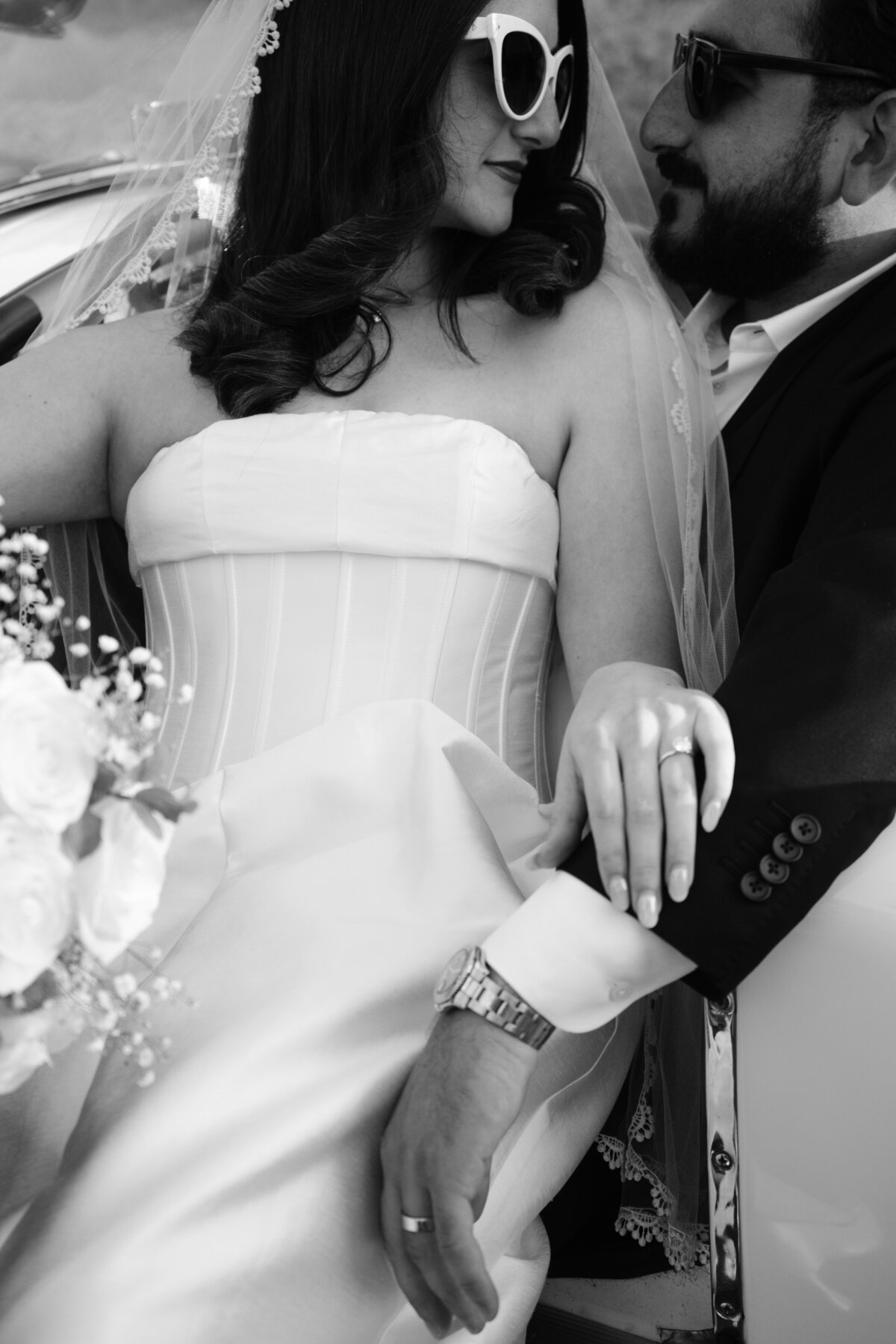 Closeup detail shot of bride and groom in Palm Springs and her structured satin dress, her flowers, ring and his watch
