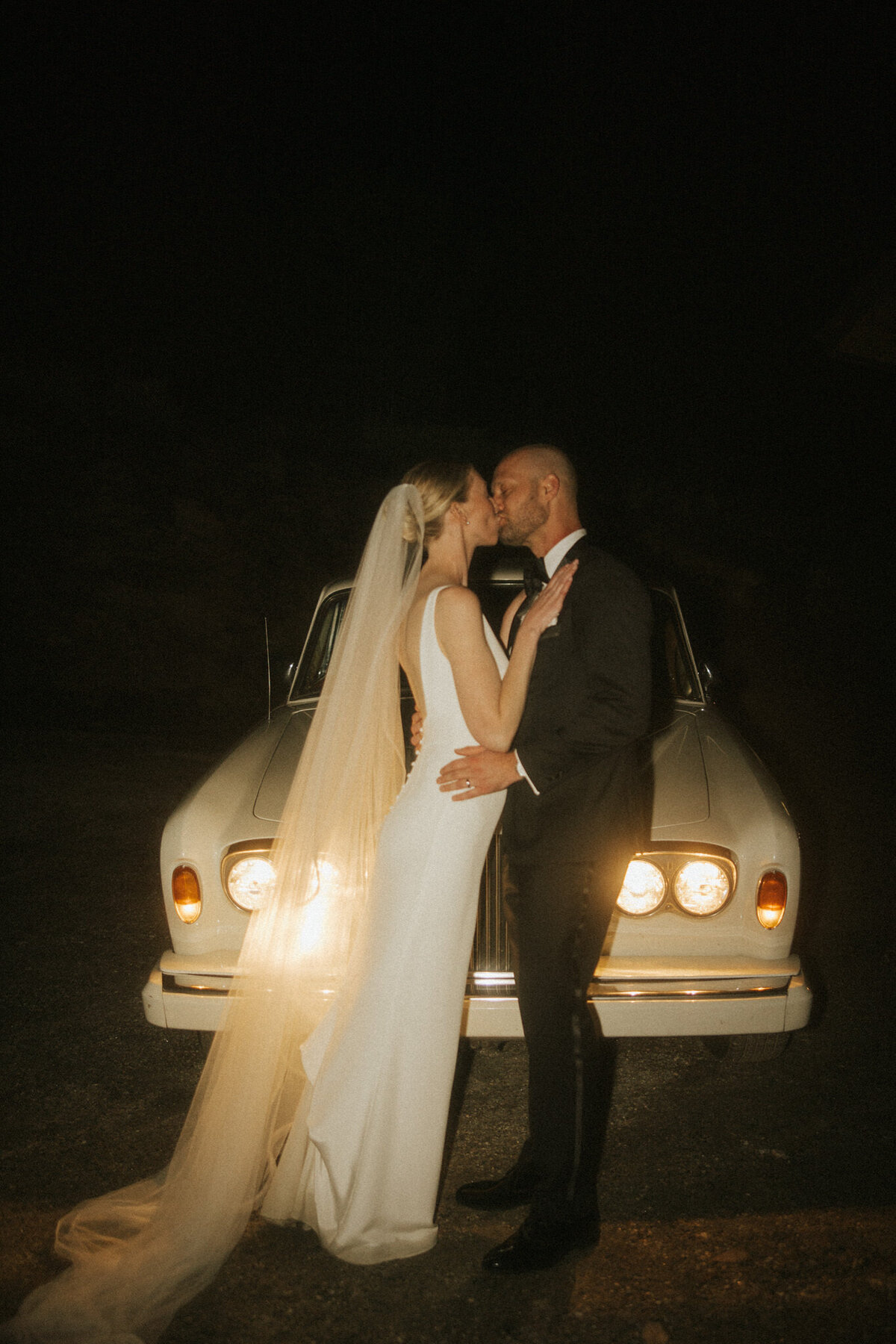 Couple posing in front of a vintage car, captured on their special day.