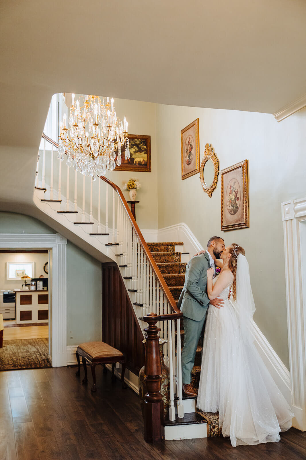 Bride and groom kissing at the bottom of a staircase at The Mansion at Keuka Lake, NY