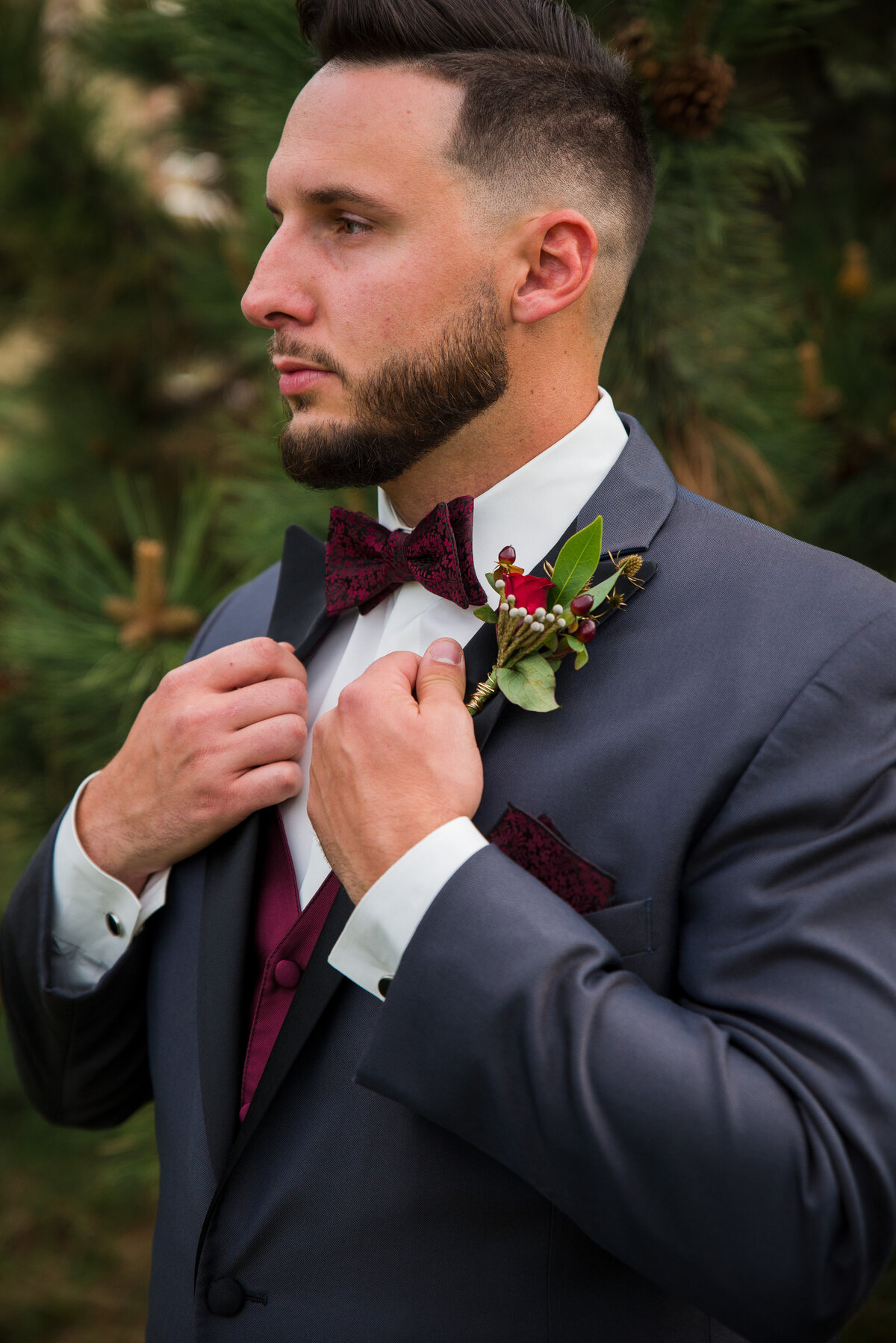 A groom looks into the distance as he adjusts his suit jacket.