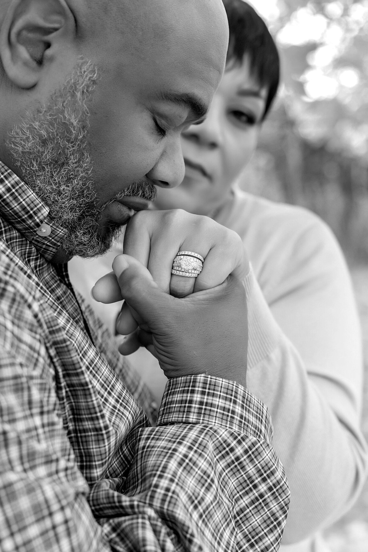 Husband kissing wife's hand with wedding right and wife is in the background