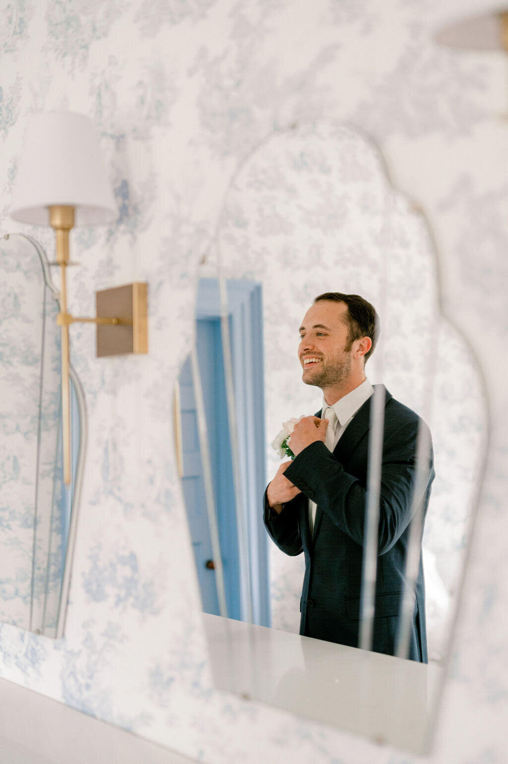 groom looking in mirror and fixing his tie