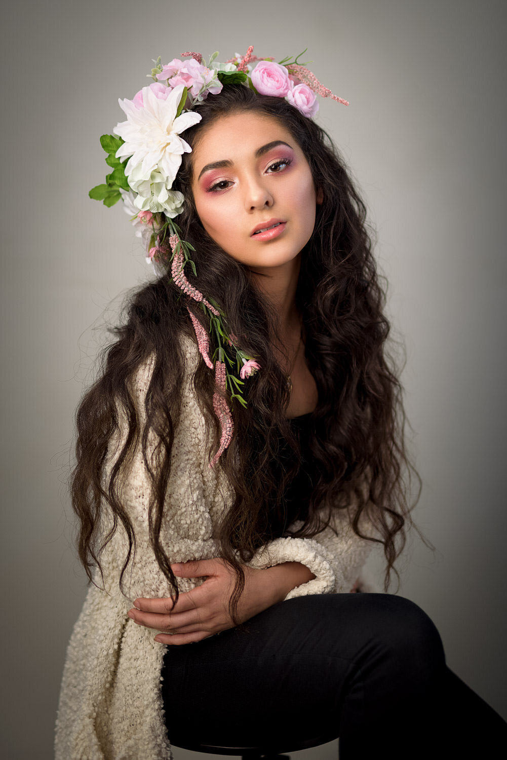 Studio headshot featuring a woman with a flower crown photographed on a warm tan backdrop for a soft, polished look in Austin, TX.