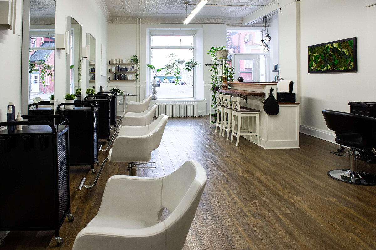 interior photo of hair salon showing hair stations, white chairs, entrance and reception.  Captured on-location at Richardson Hair Design by Ottawa branding photographer JEMMAN Photography
