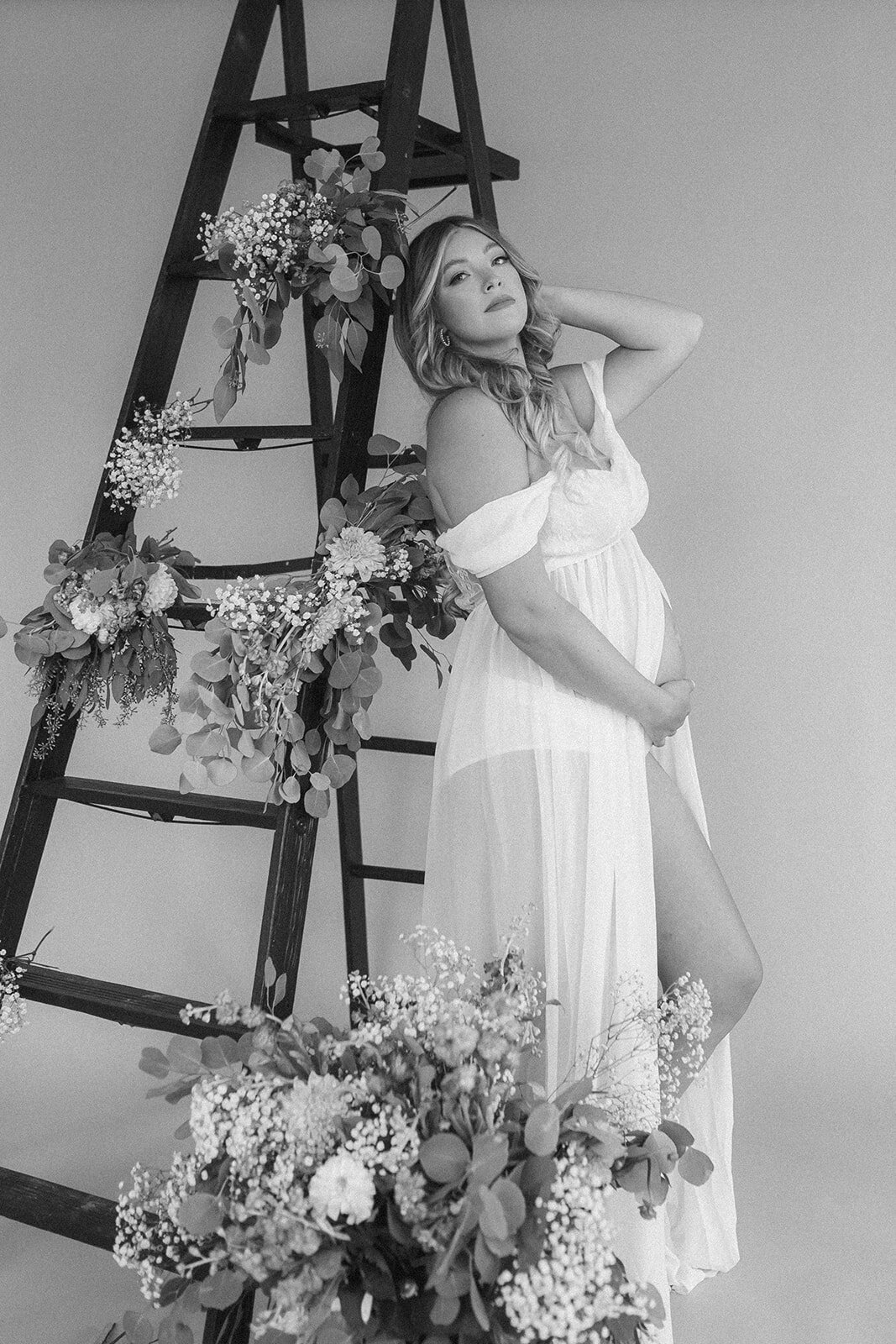 A pregnant woman holds her belly surrounded by flowers