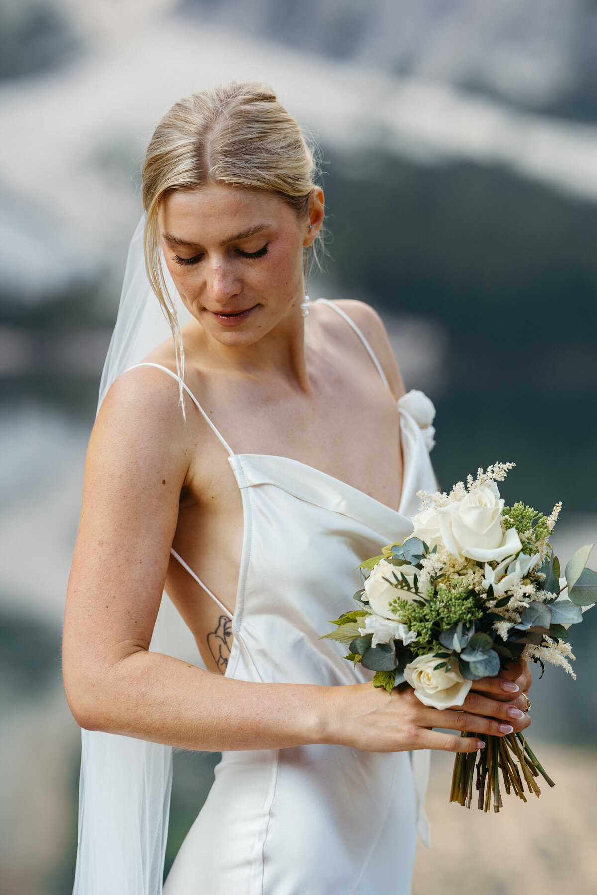 Bride smiling with bouquet against mountain backdrop