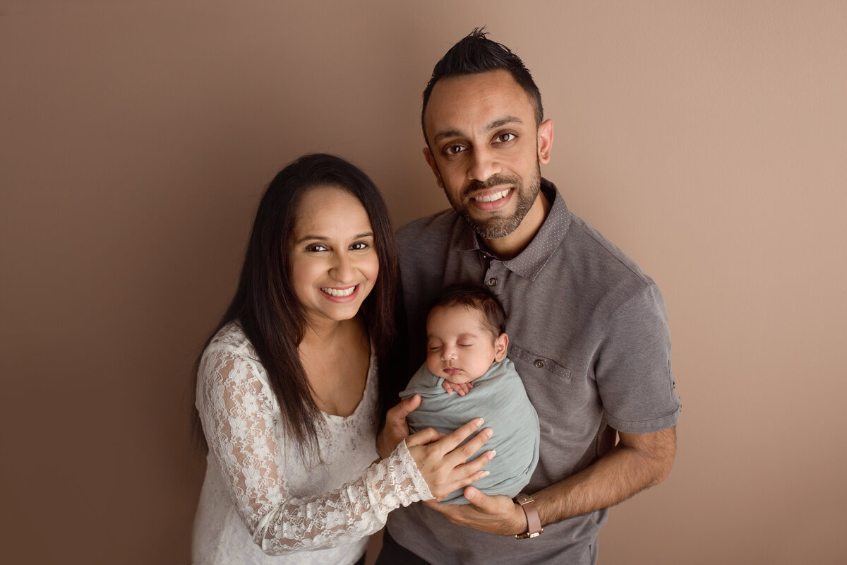 new jersey family posing with their baby boy wrapped in blue swaddle