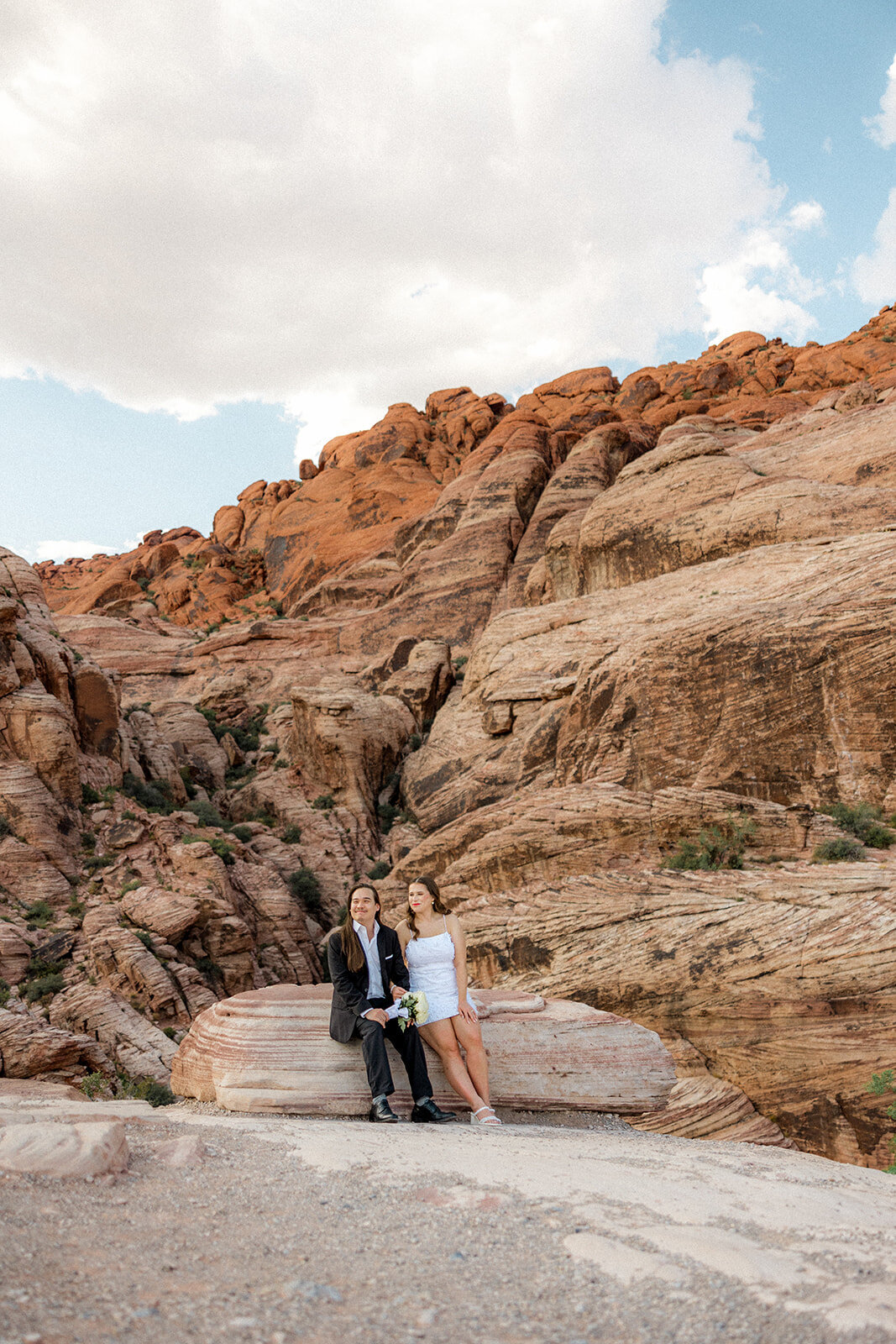 Engaged couple sitting on rock at the Red Rock Canyon smiling