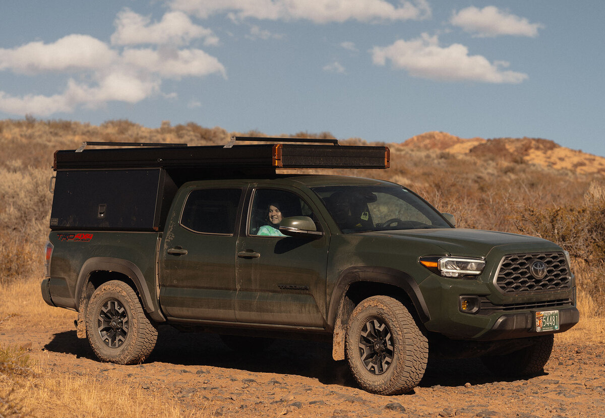 a truck with a pop up camper drives through the Moab, Utah desert on its way to an elopement