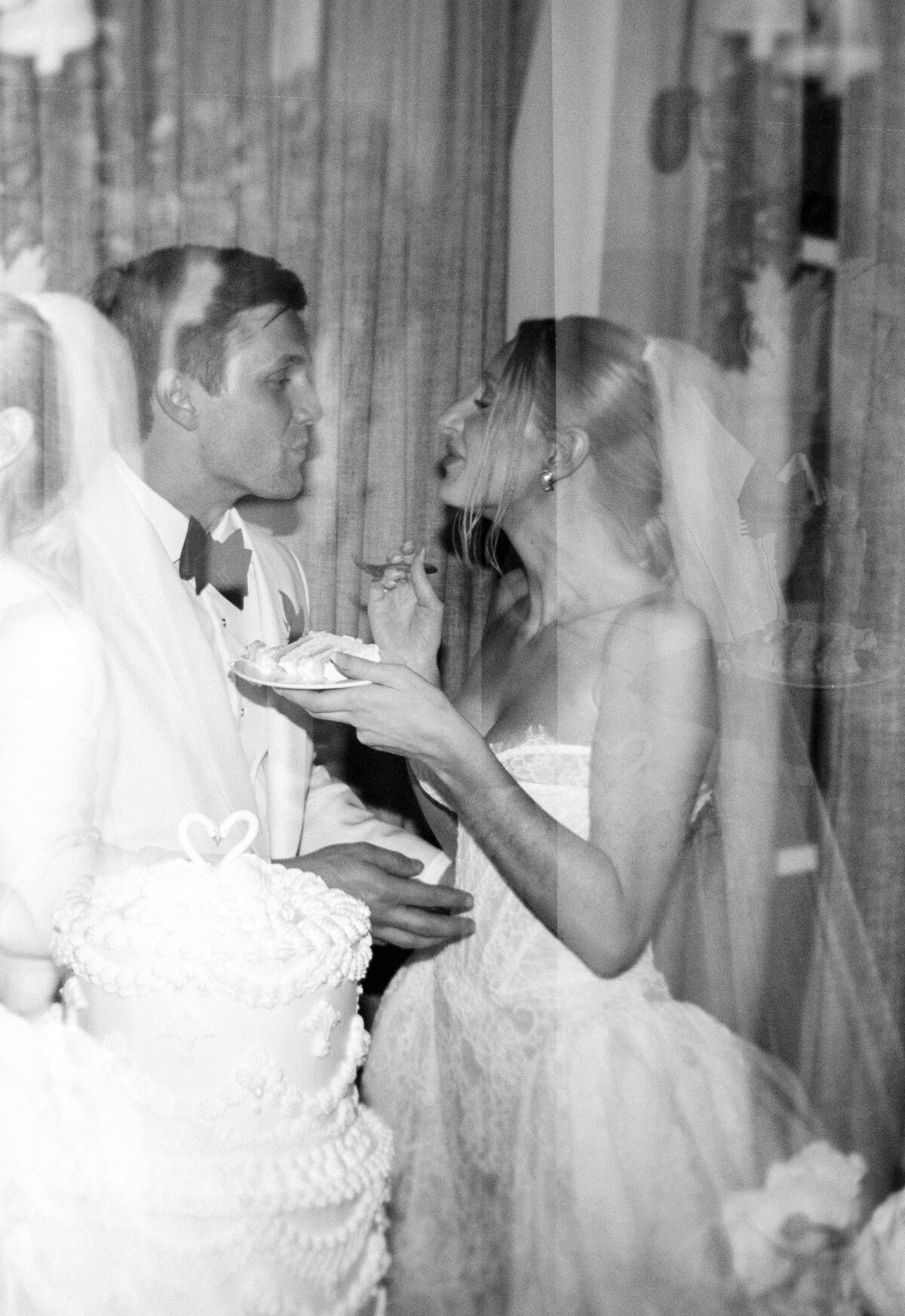 Newlyweds cutting their wedding cake in a film black and white photo