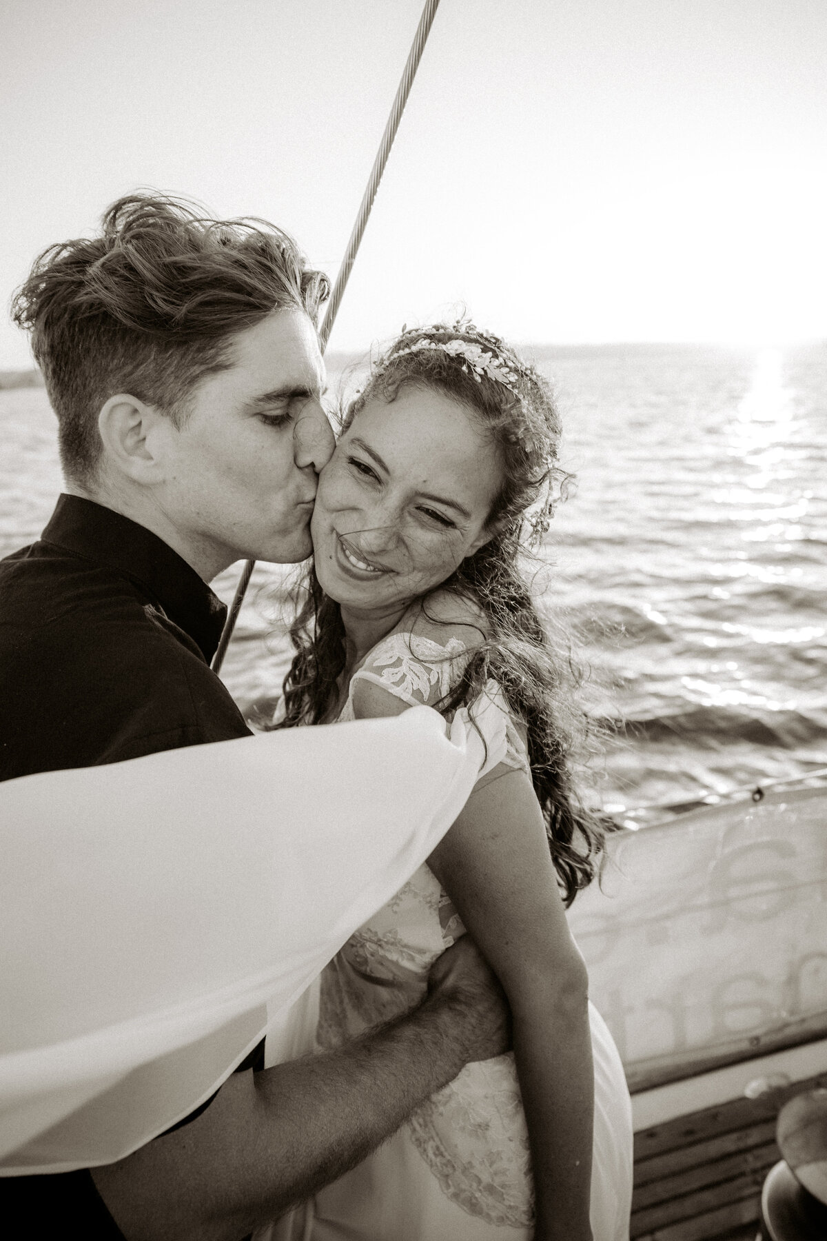 Bride and groom portrait on yacht in San Diego in black and white groom is lovingly kissing the bride on the cheek