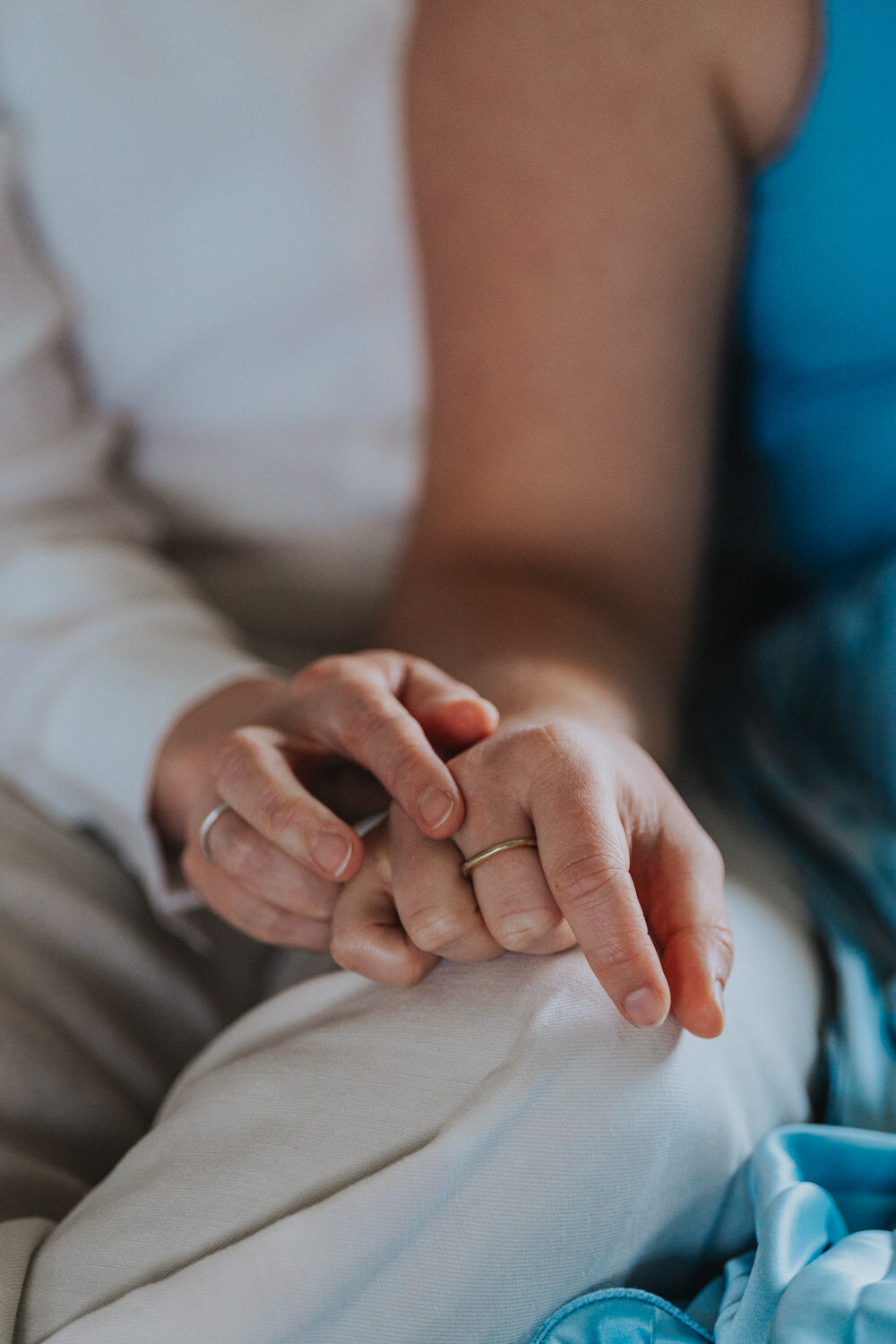 The wedding bands of two women who are resting their hands on each other 