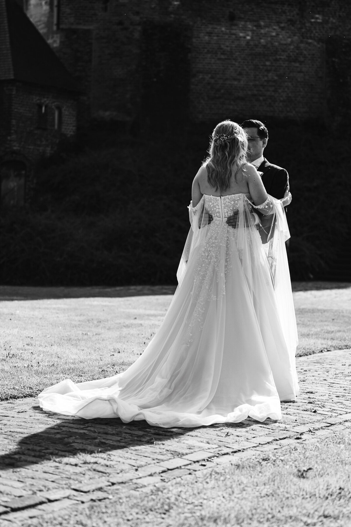Een romantisch moment van het bruidspaar dat samen geniet op een zonnig grasveld, vastgelegd door IMAI Wedding.