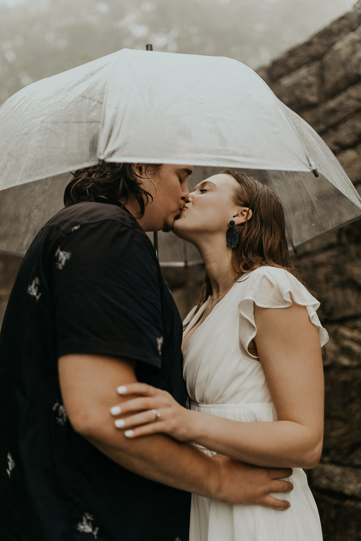 couple kisses under clear umbrella