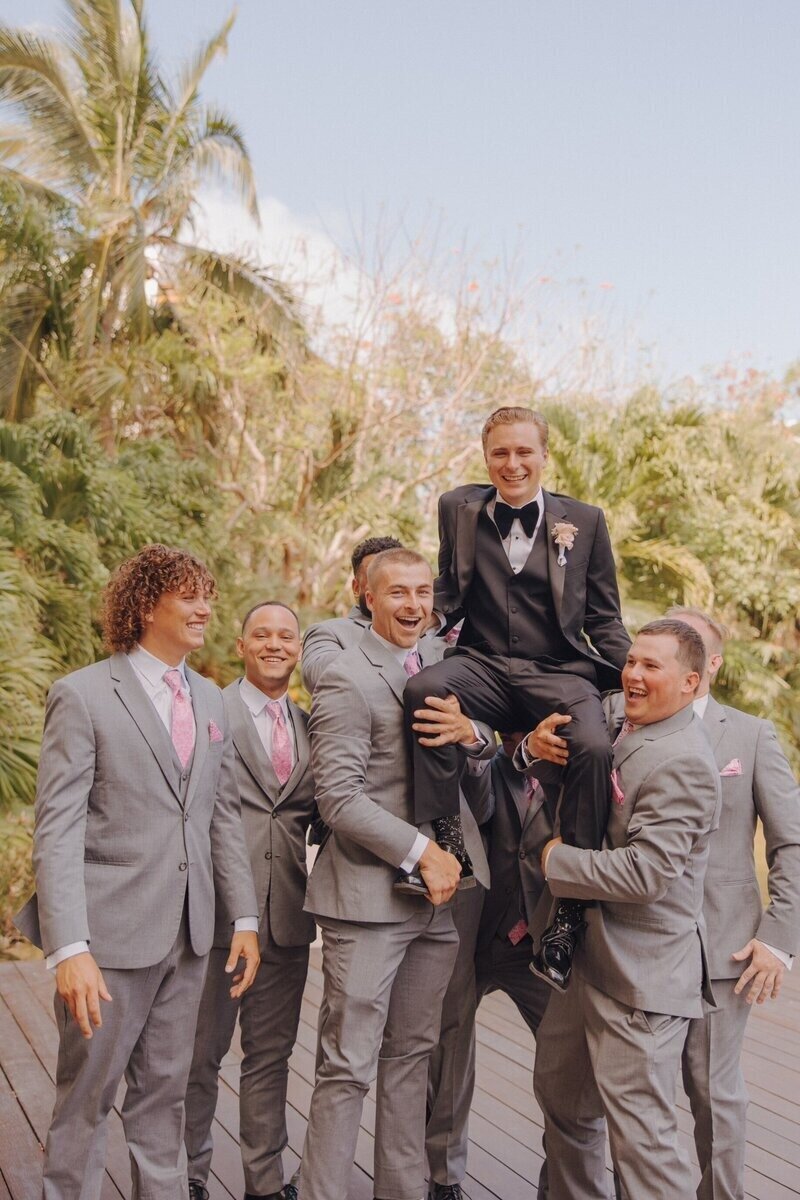 Groomsmen holding groom up at wedding planned by travel planner for destination weddings