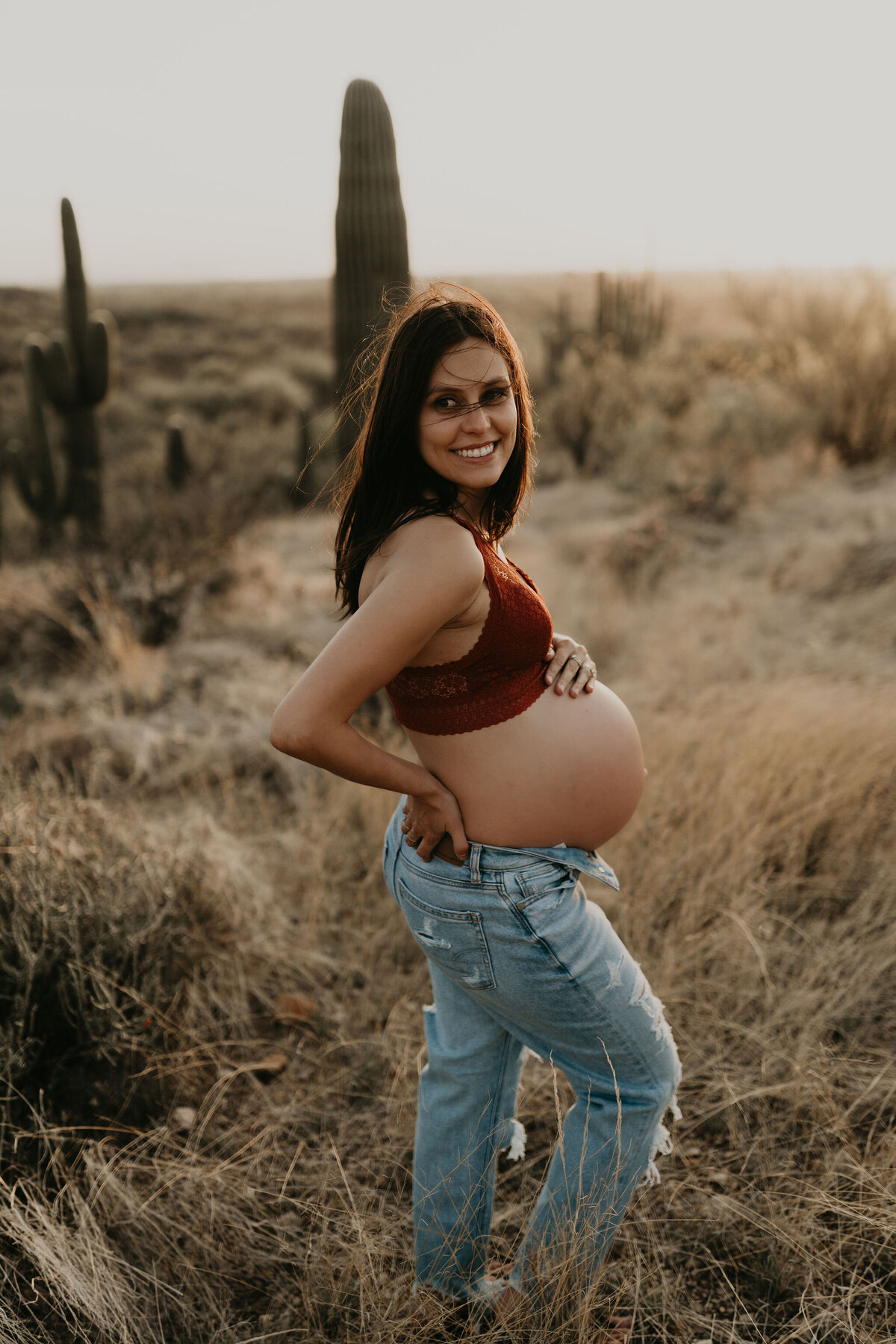 candid maternity portrait of mom in bralette and jeans