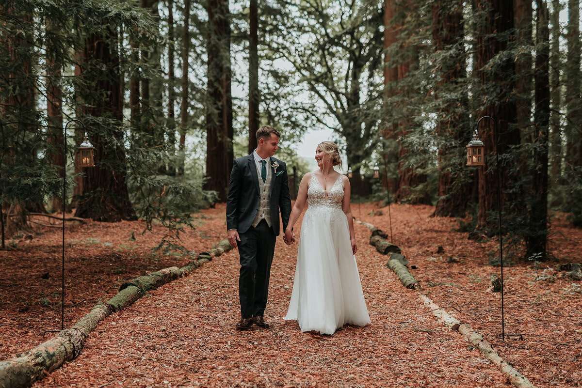 Bride & Groom walking along woodland pathway in the Redwoods at Two Woods Estate