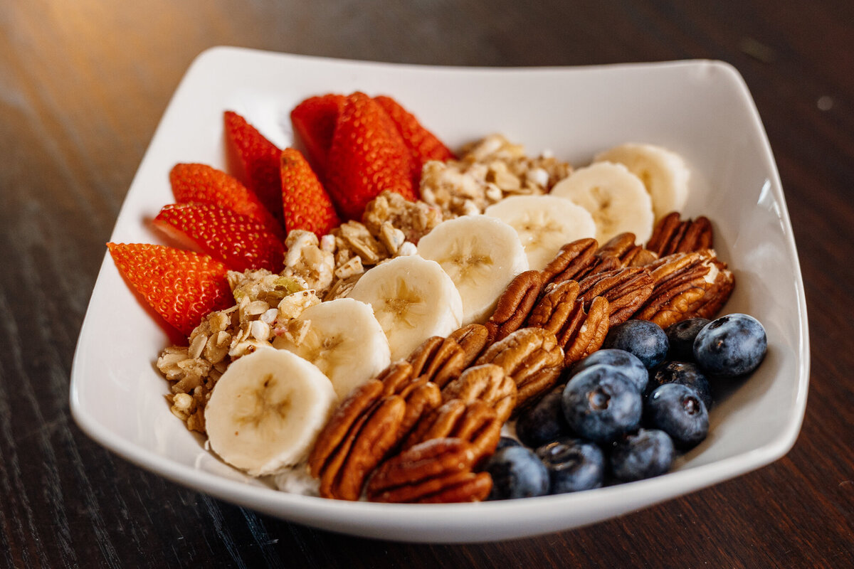 A bowl of oats, fruits and nuts sits on a table.