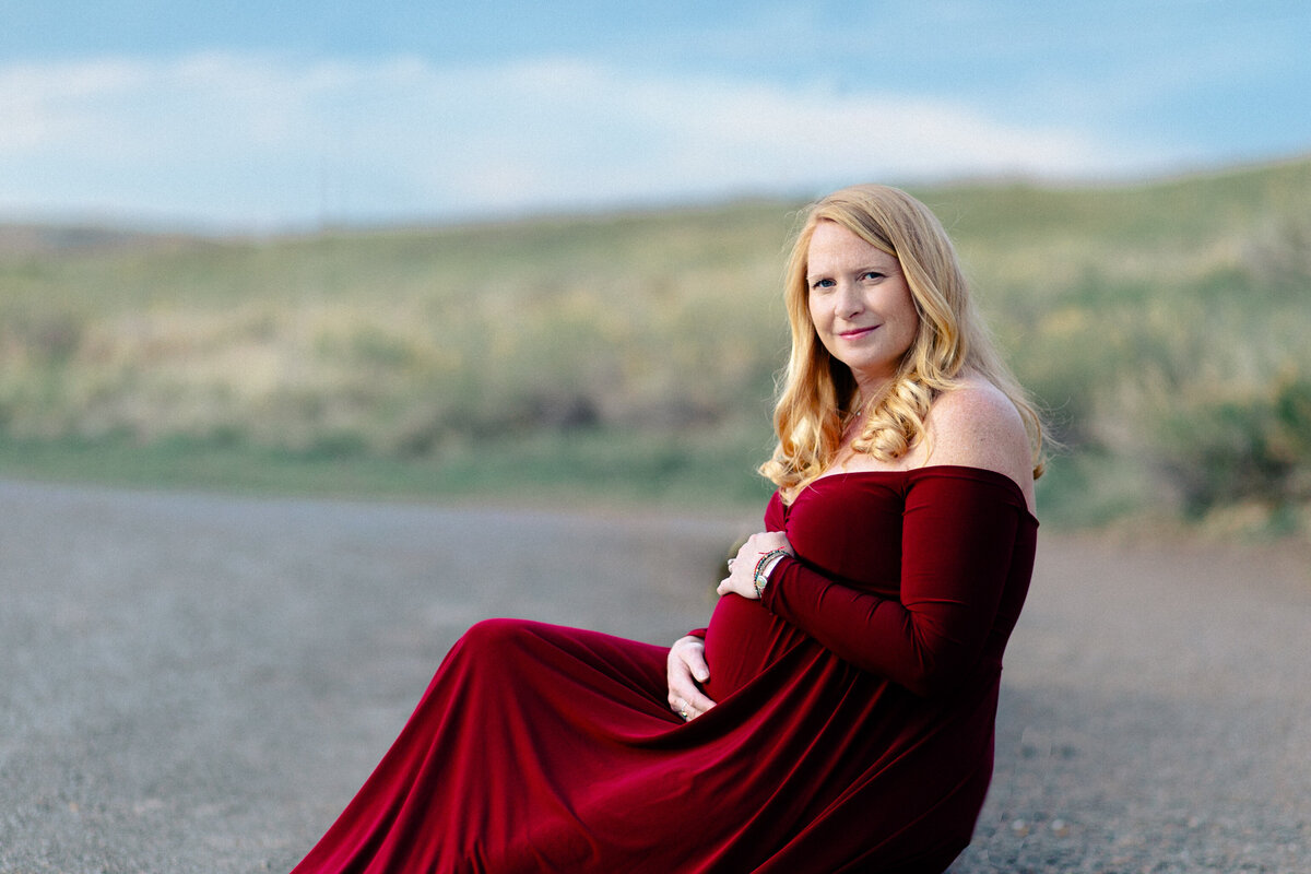 maternity portrait of a woman in a red dress and a baby bump