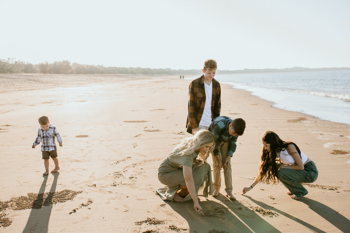 Family explores the beach looking for crabs during sunset. 