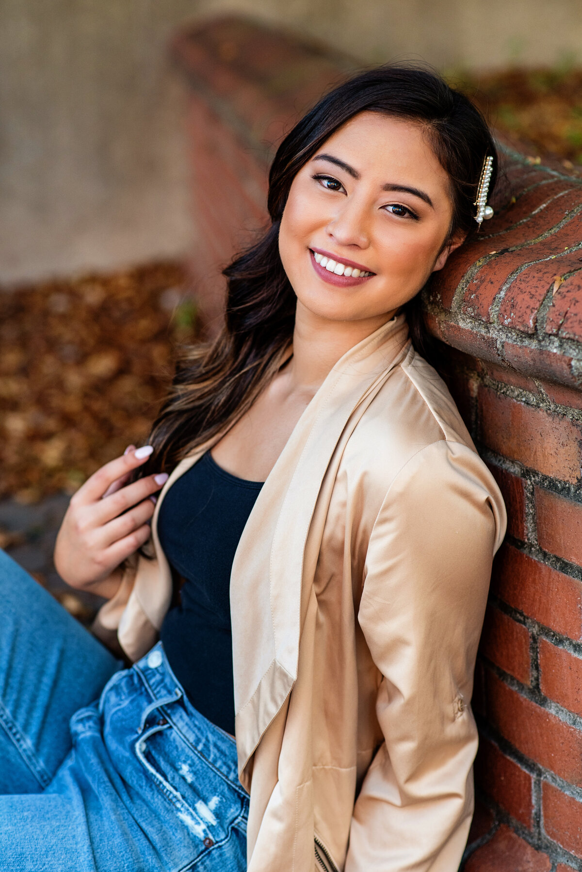 Senior girl leans against brick wall and smiles during her portrait session downtown Richmond, VA.