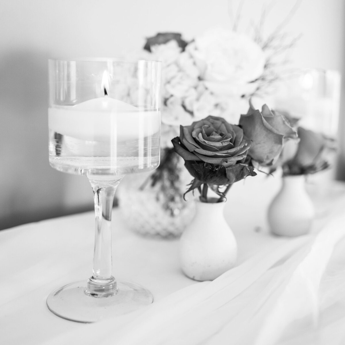 black and white photo of roses and tea candles sitting on a shelf