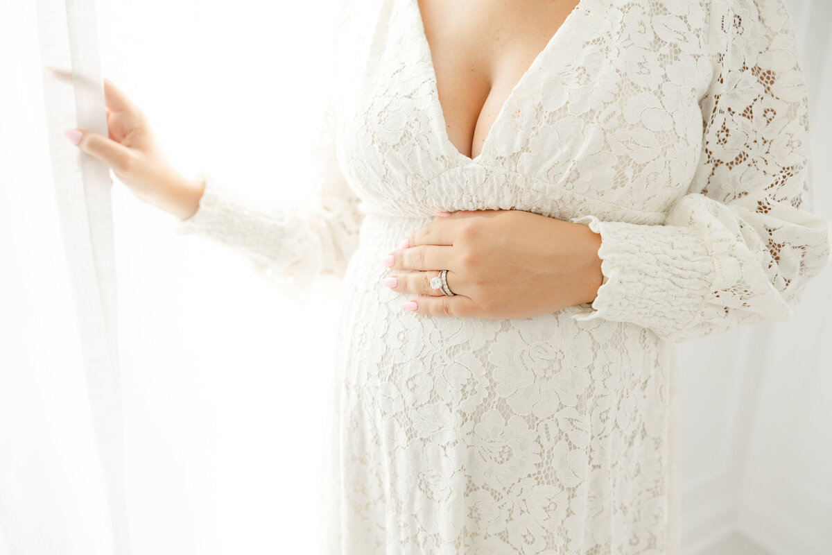 Mom in lace dress with hand on pregnant belly for Northern Virginia Maternity Photography session