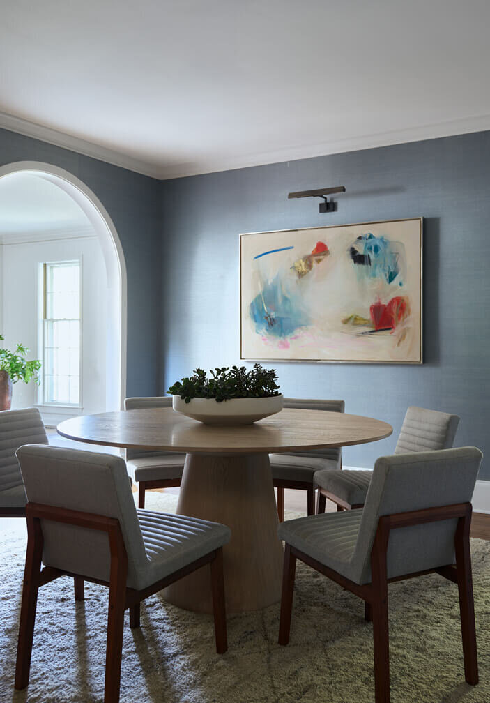 Modern dining table with contemporary art and blue grasscloth wallpaper in a historic Hingham home, designed by New England interior designers blending style and tradition.