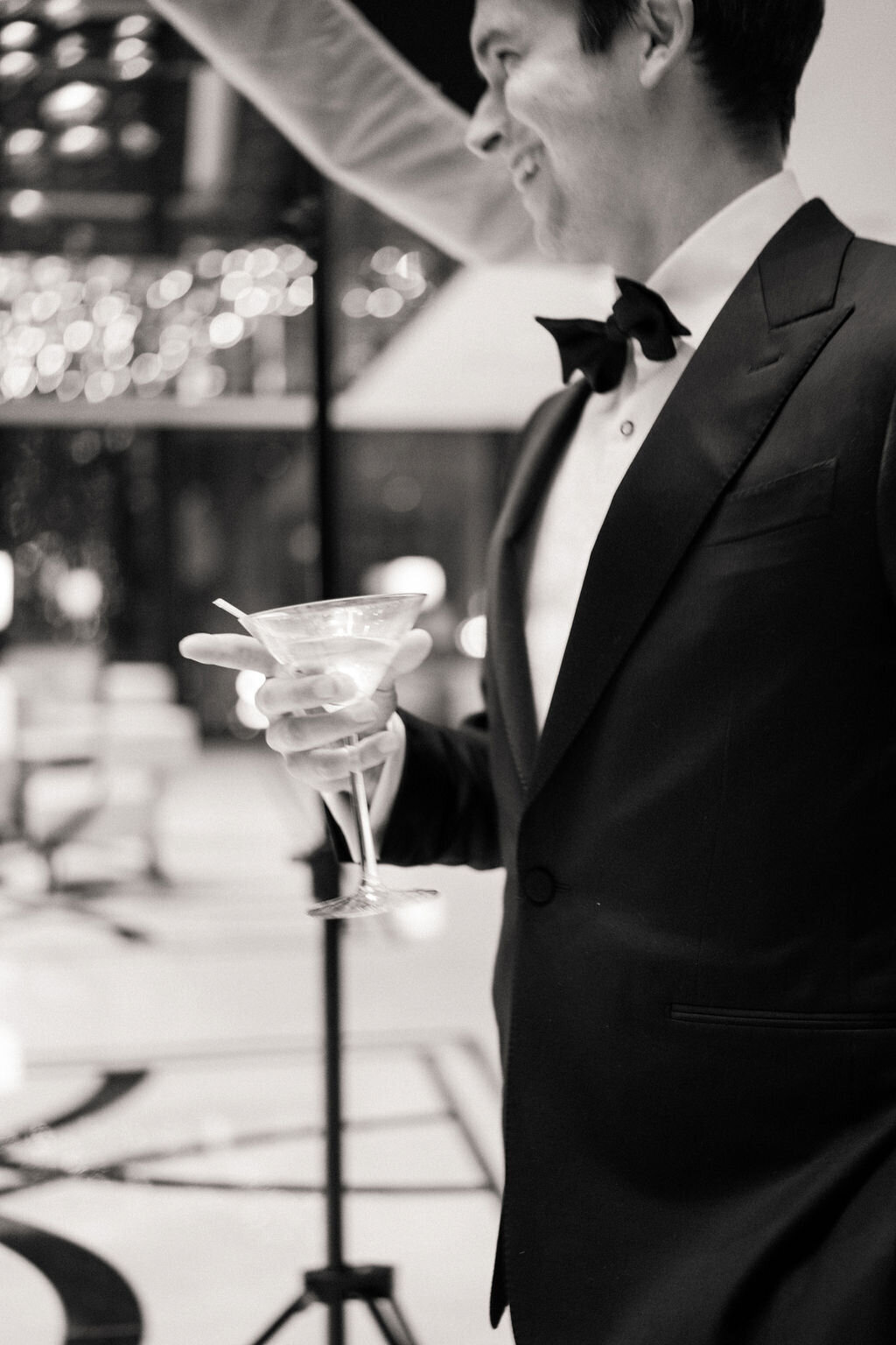 Close up black and white photo of a man holding a martini. 