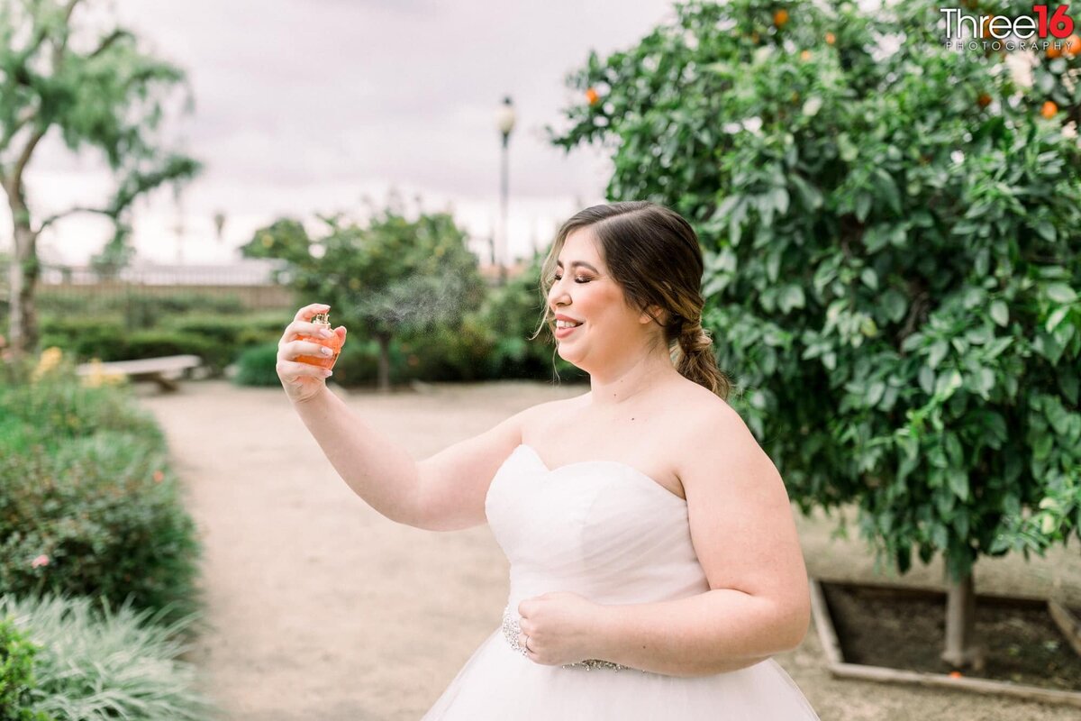 Bride spritzes herself with a touch of perfume