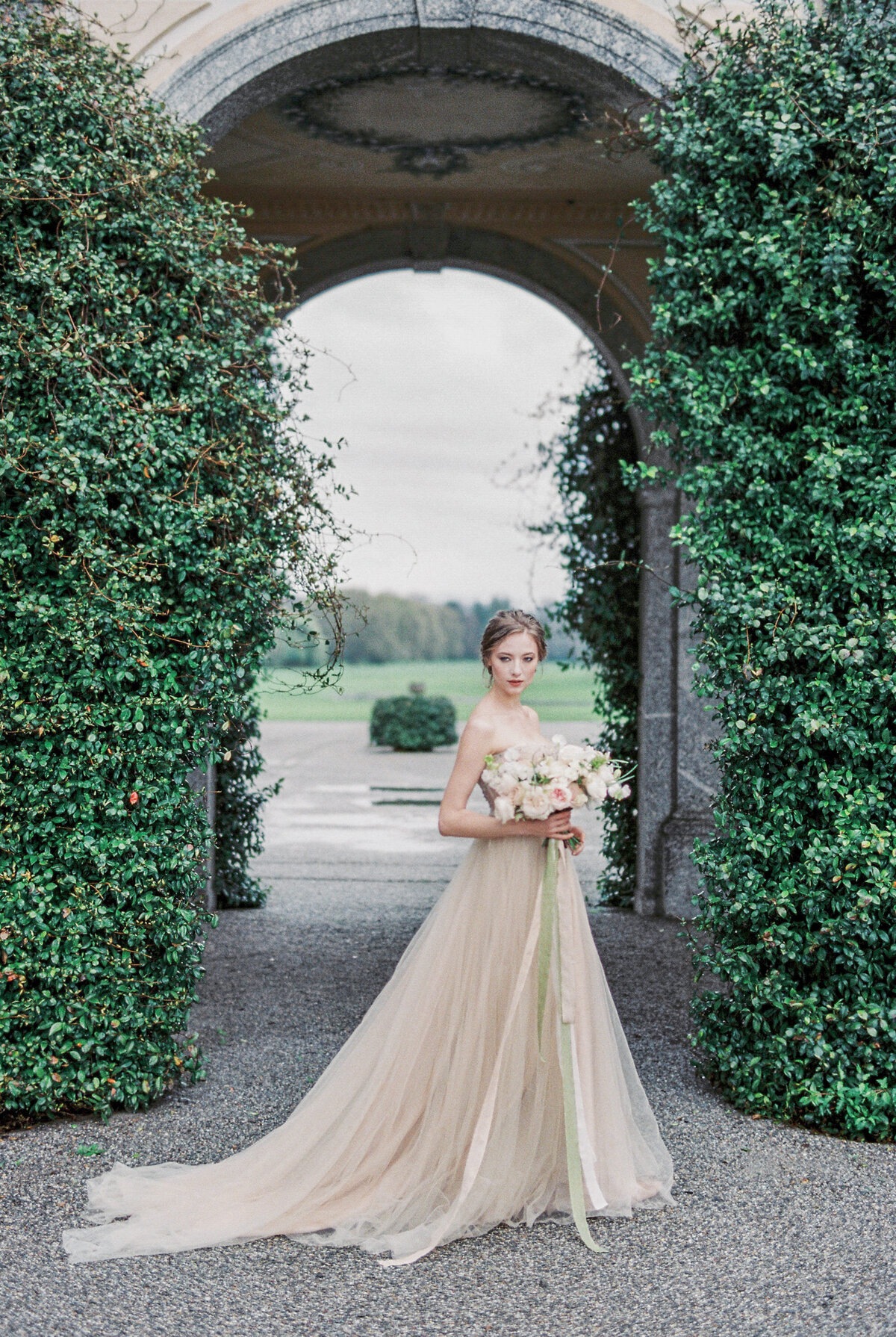 2bride-with-bouquet-stands-near-old-villa-como-italy