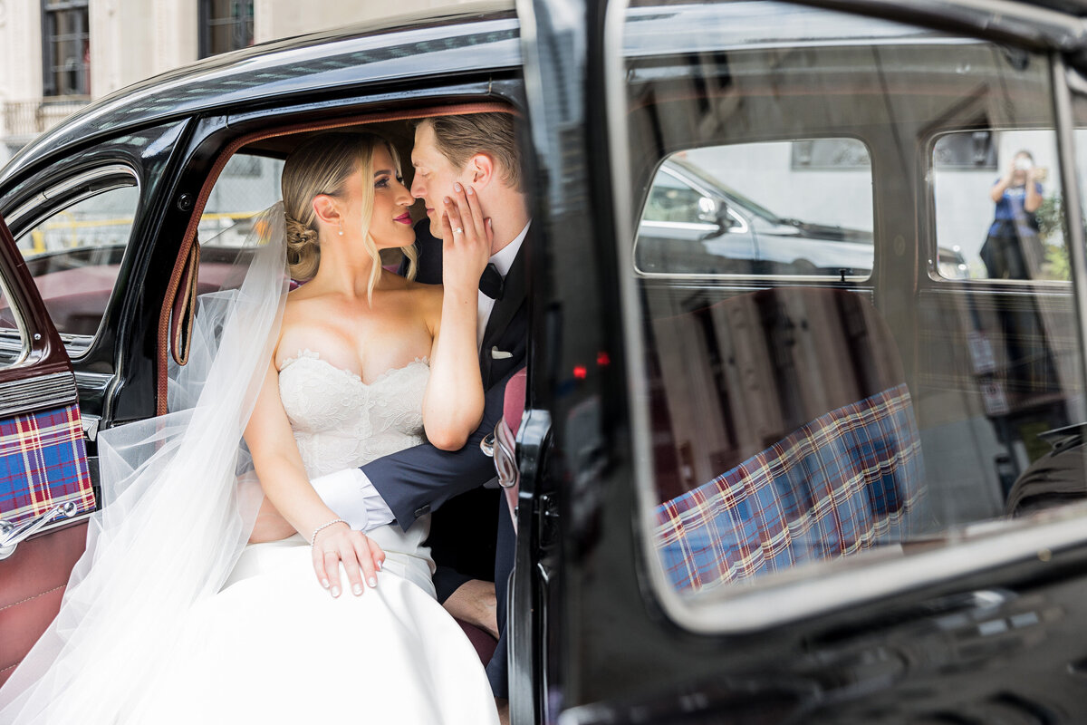 wedding couple snuggling with each other in the back of the classic pittsburgh car