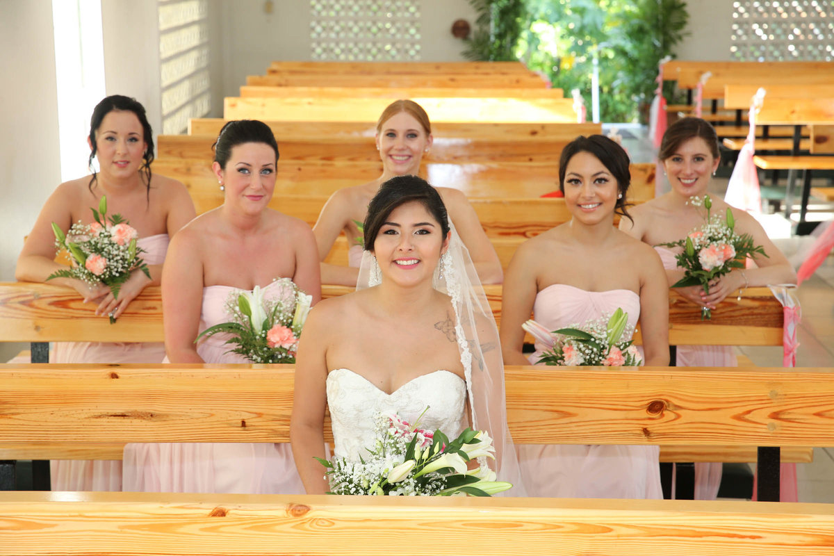 Bride with bridal party sitting in church pews. Photo by Ross Photography, Trinidad, W.I..