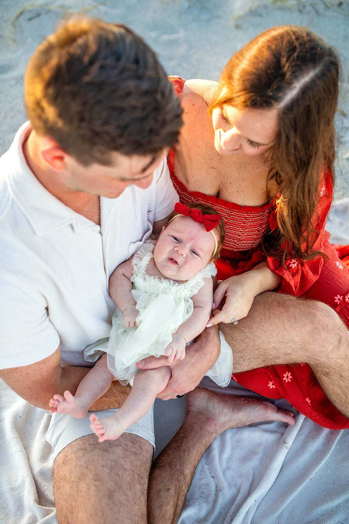 Close up portrait of family focusing on baby girl with the parents looking down at her 