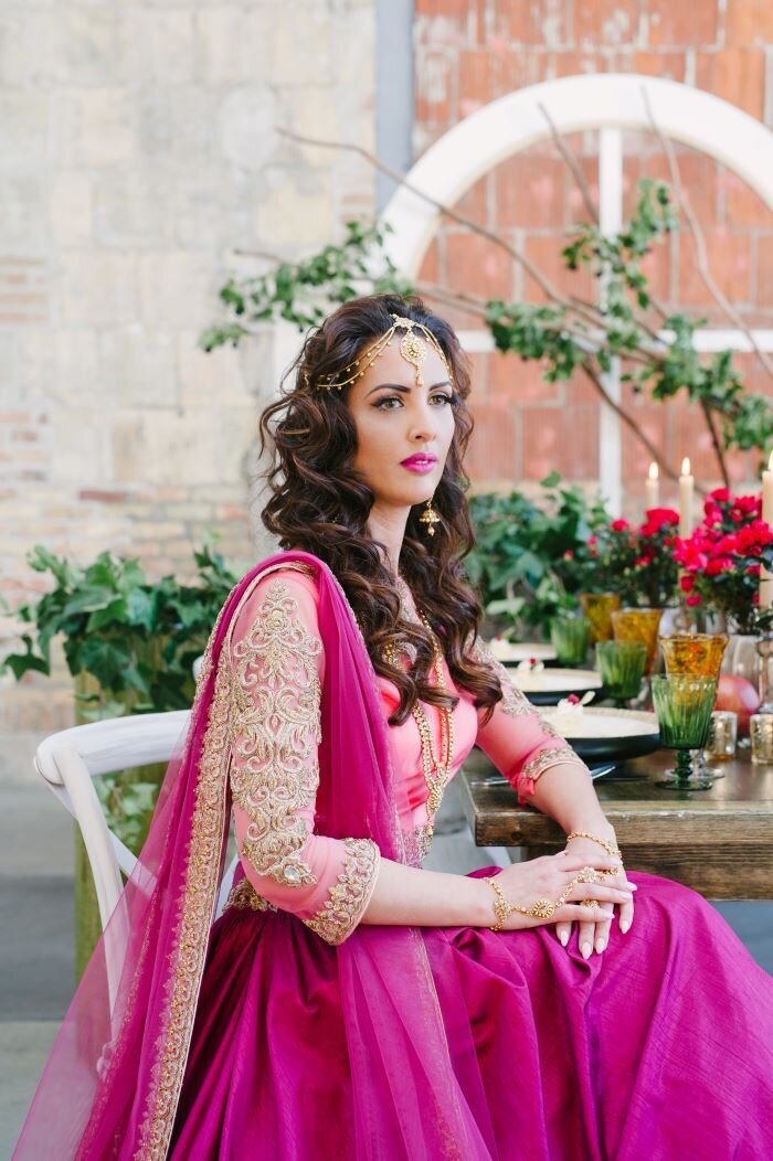 Luxurious Ottawa Indian bridal look: Heavy mascara, jeweled eyeliner, and glossy lips complement her ornate attire.