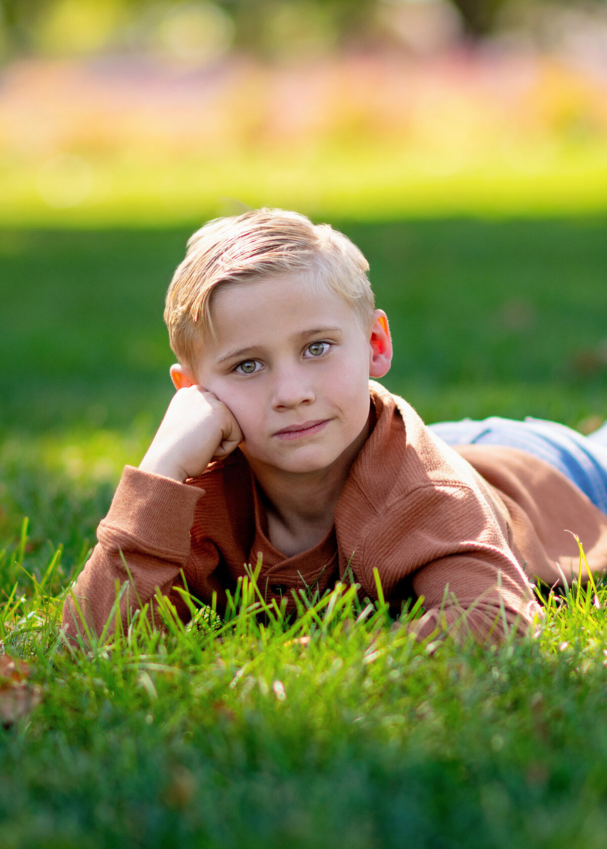 A carefree kid sprawls out on a grassy lawn, soaking up the warm weather