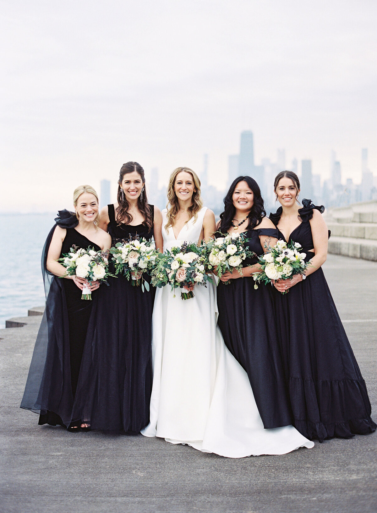The bride standing in the middle of the group of bridesmaids with the city of Chicago in the background. 