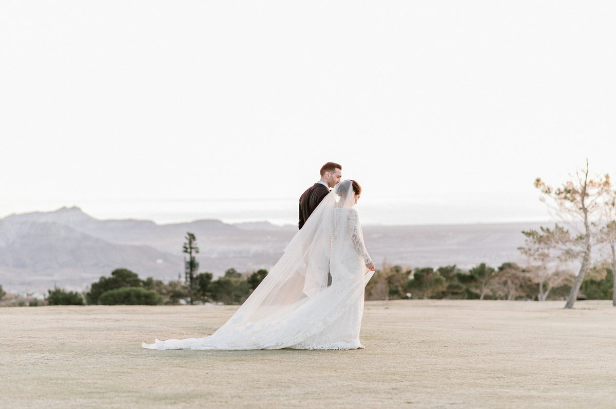 couple walking in open field with mountains in background