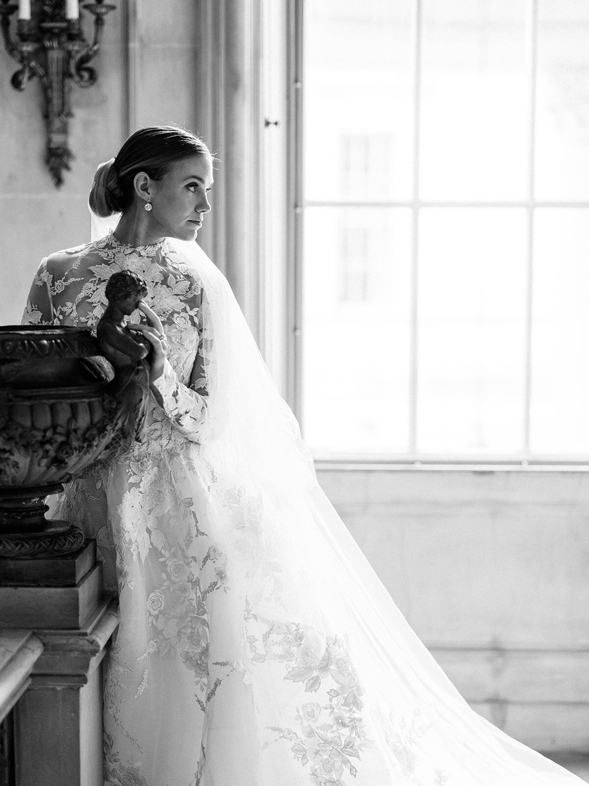 A classic black and white portrait of a brides profile showcasing her veil through the window light